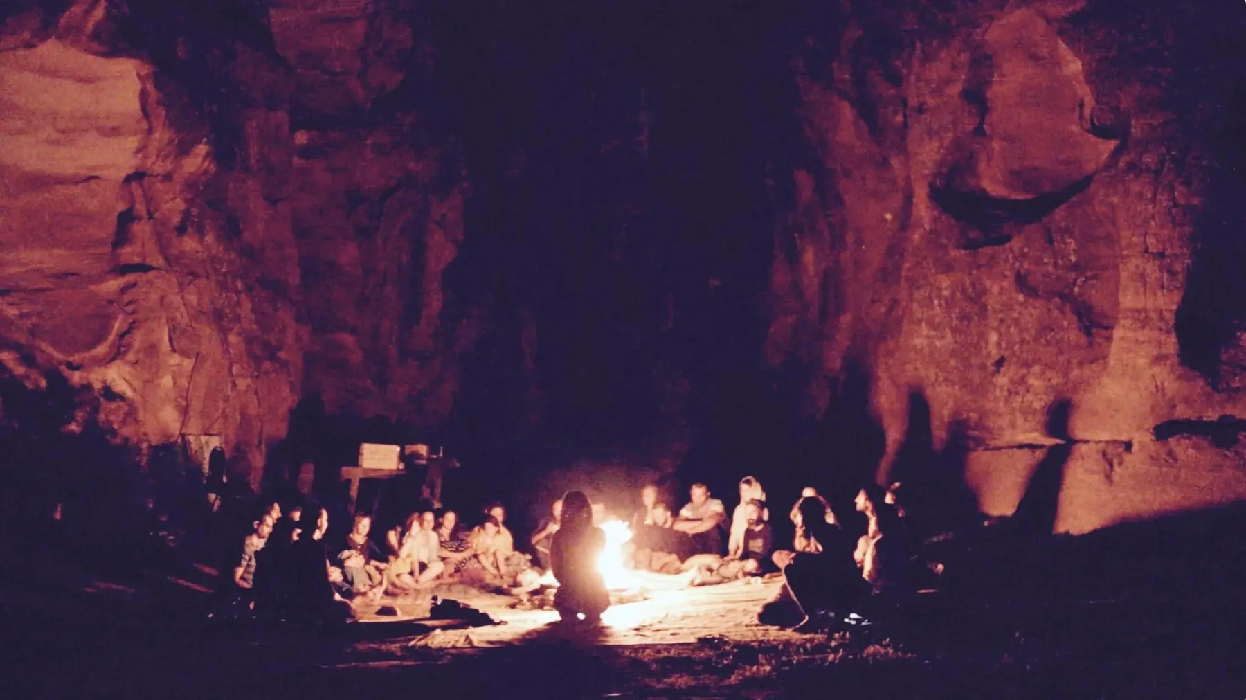 A gathering around a fire in a sandstone canyon at night