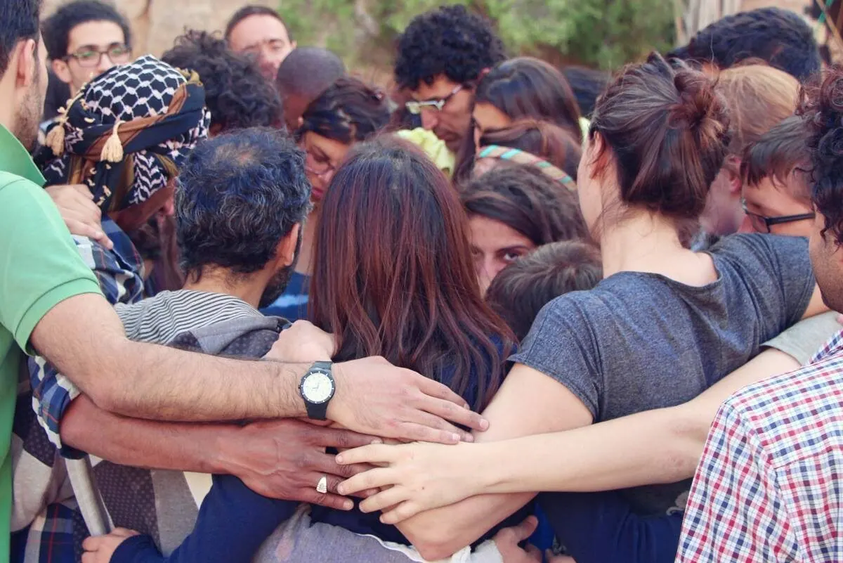 A tight group huddle, arms around each other